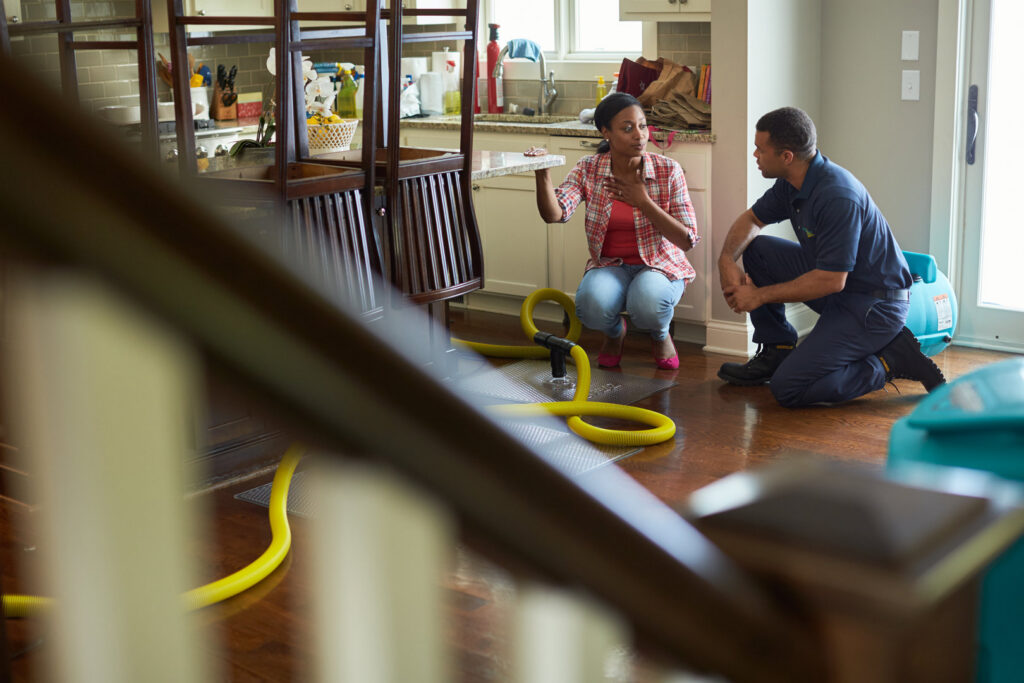 A technician from Xtreme Clean Restoration & Carpet Care discussing a water damage restoration job with a client in San Antonio, TX