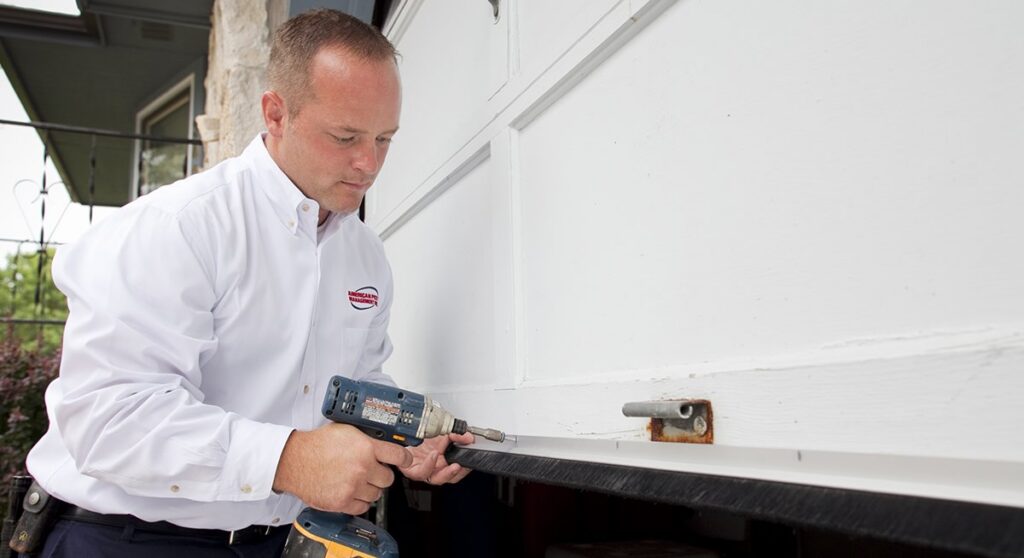 A pest control technician drilling an exterior structure, possibly for exclusion work, by American Pest Management in Saint Petersburg, FL.