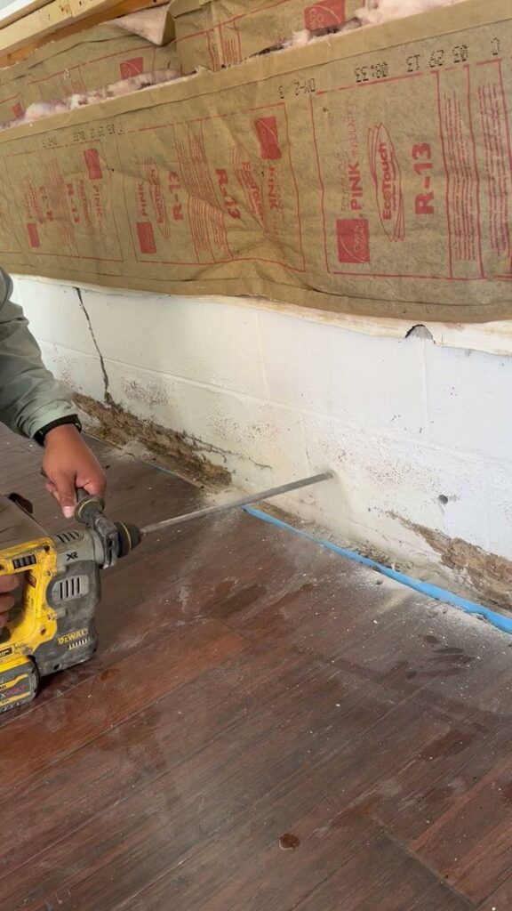 A technician drilling into a foundation wall for termite treatment by Global Green Termite & Pest Control LLC in Hampton, VA.