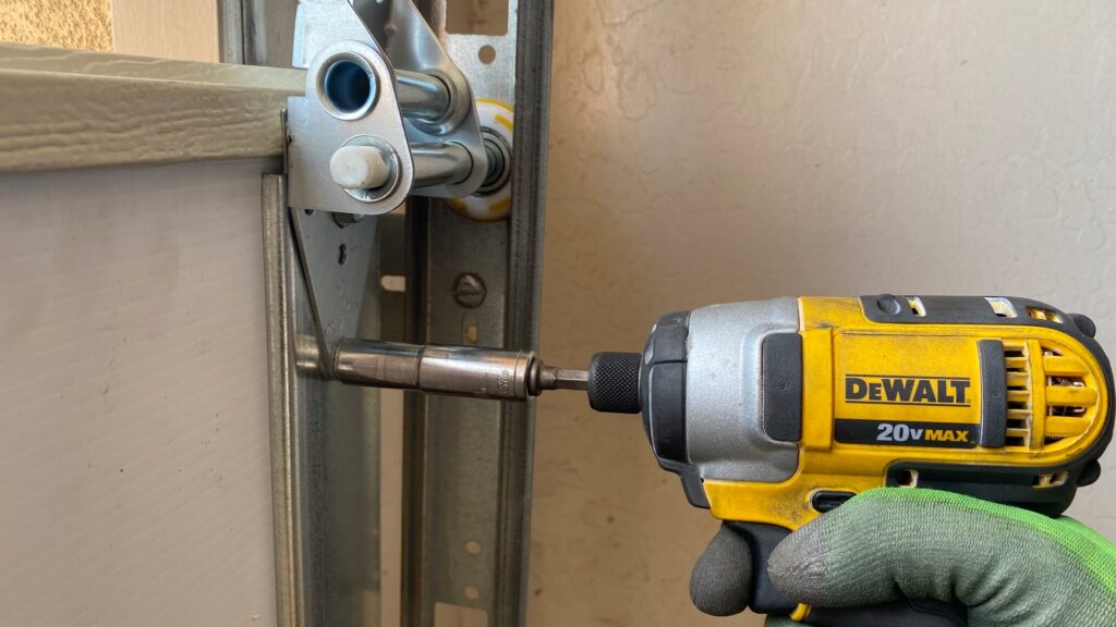 A technician drilling a garage door hinge during a repair by Nate's Garage Door Repair in Scottsdale, AZ.