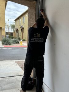 A technician from 101 Garage Doors using a drill to work on a garage door track or frame in Phoenix, AZ.
