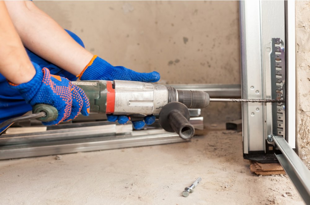 A technician drilling a garage door track during installation for Iconic Garage Door Service in Queen Creek, AZ