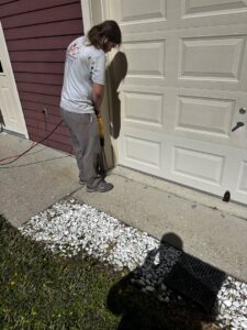 A JPC Exterminating, LLC technician drilling for termite treatment near a garage in New Orleans, LA.