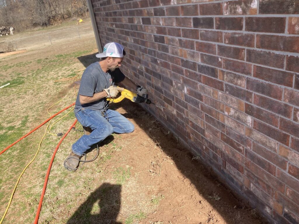 A technician from Roach's Termite Service Inc. drilling for termite treatment at a property in Oklahoma City, OK