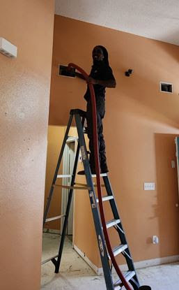 A technician performing duct cleaning on a high ceiling vent for Sterling Service of Florida Inc in Tallahassee, FL.