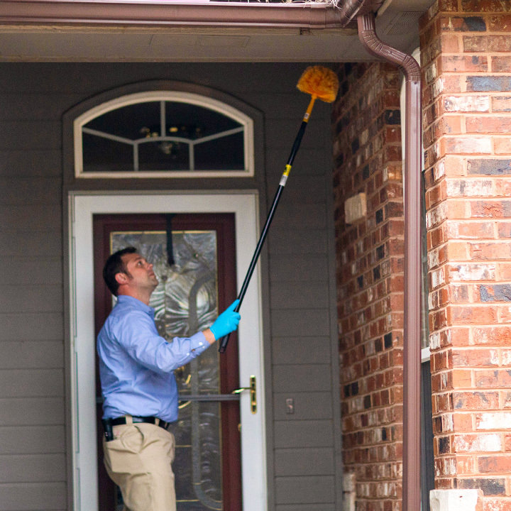 A Miller Pest & Termite technician dusting gutters and eaves for pest control in Kansas City, MO