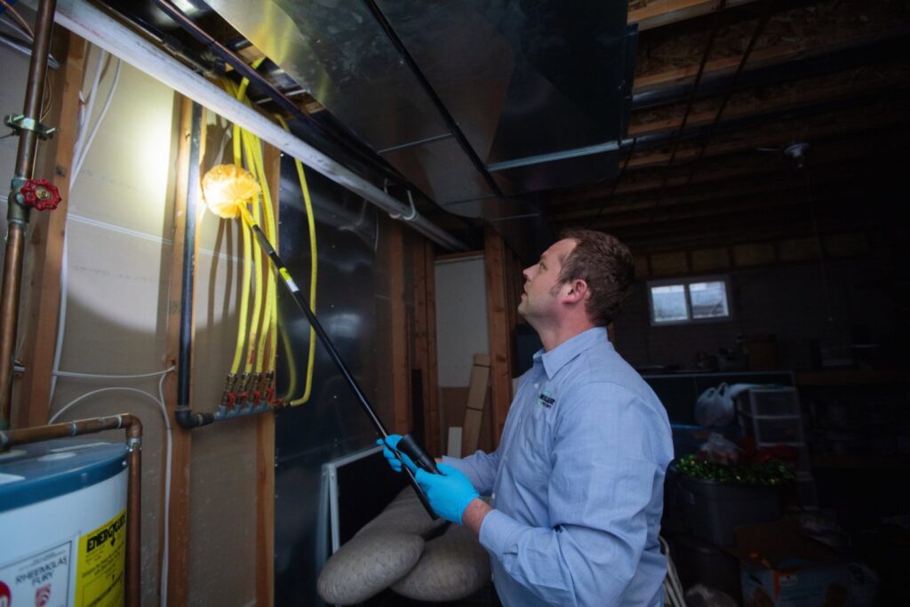 A Miller Pest & Termite technician dusting an overhead area for pest control in Kansas City, MO