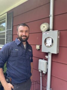 A technician inspecting an electrical panel and meter, providing electrical services from All Comfort Services in Madison, WI