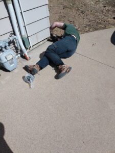 A pest control technician performing an exterior treatment or sealing work on a house for Enviro-Pest Solutions in Waterloo, IA.