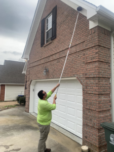 A Nooga Pest Control technician performing exterior pest treatment on a brick house in Chattanooga, TN