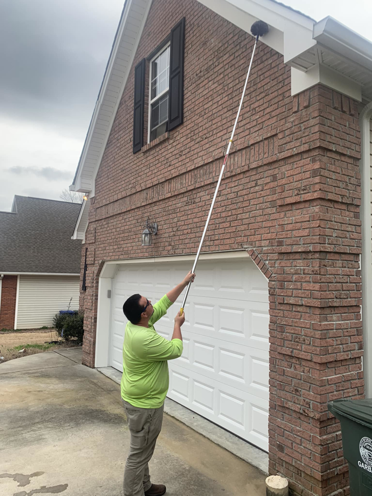 A Nooga Pest Control technician performing exterior pest treatment on a brick house in Chattanooga, TN
