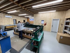 A technician fabricating metal ductwork in a workshop, with a mini-split unit visible, for A/C Company Since 1988 in Murfreesboro, TN.