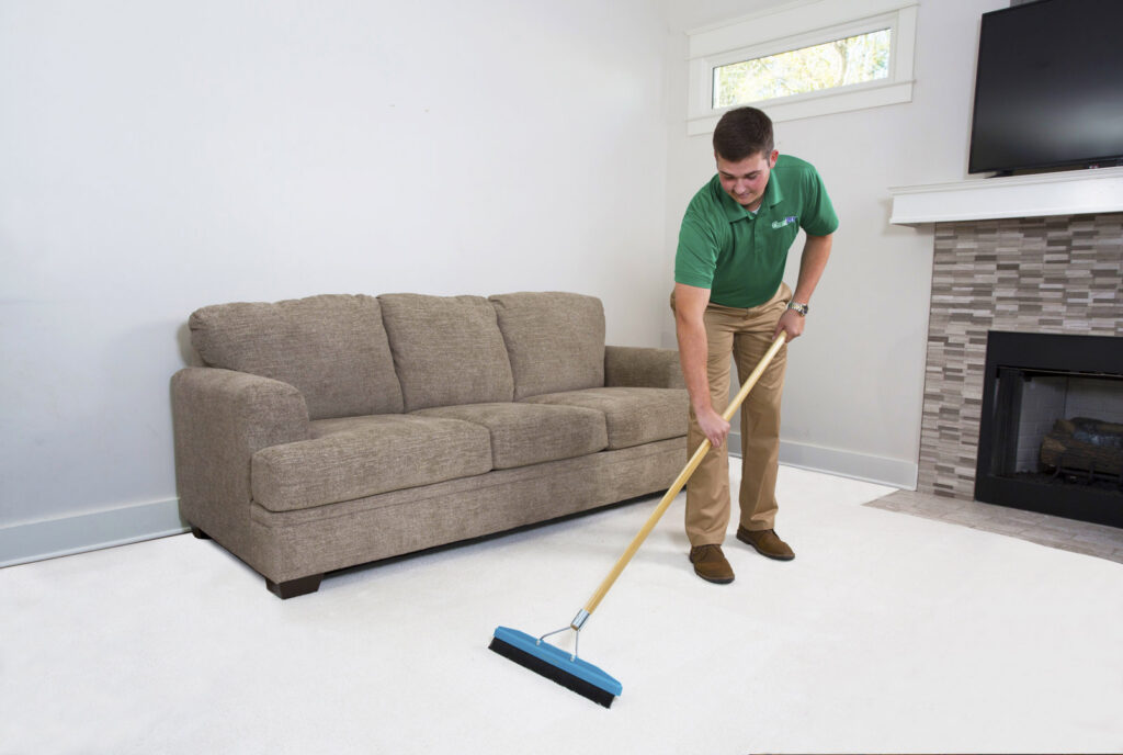 A Precision Chem-Dry Of DFW technician grooming a freshly cleaned carpet with a rake in a living room in North Richland Hills, TX.