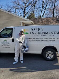 A technician in a hazmat suit standing by an Aspen Air Duct Cleaning company van in Methuen, MA, ready for service.