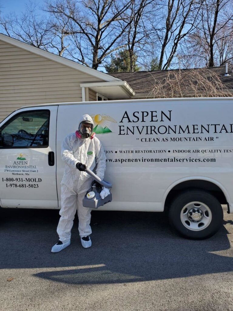A technician in a hazmat suit standing by an Aspen Air Duct Cleaning company van in Methuen, MA, ready for service.