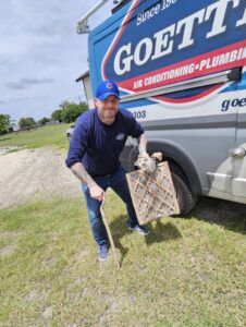 A Goettl Austin technician holding a dirty HVAC air filter next to a service van in Austin, TX