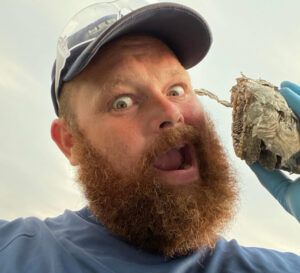 A Herman Pest Control Services technician in Minot, ND, holding a small wasp nest or comb after removal.
