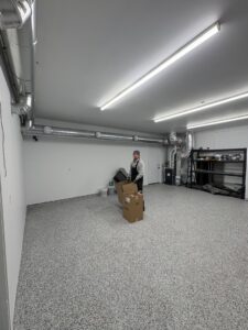 An A&E Heating & Cooling technician in a garage with newly installed HVAC ductwork in Fort Worth, TX.