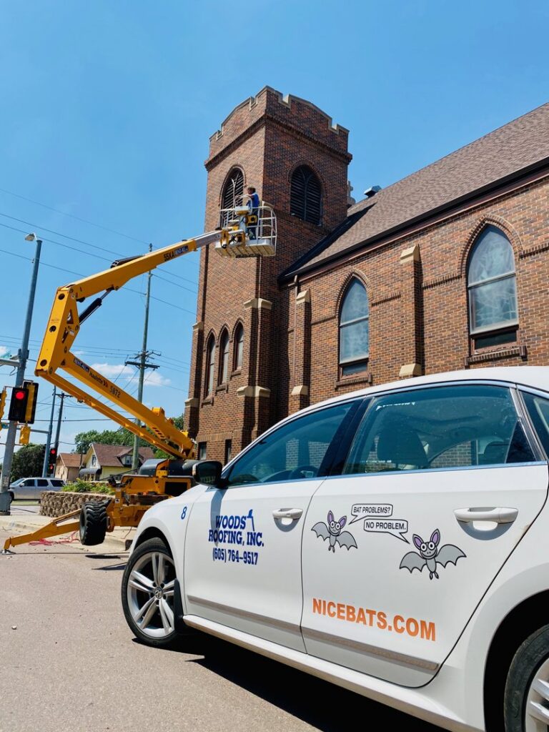 A NiceBats.com technician in a lift inspecting a building for wildlife control, in Sioux Falls, SD.