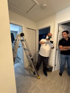 A technician wearing a respirator mask performing an indoor pest inspection for PNP Pest Solutions LLC in Miami, FL.
