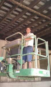 A D&J Pest Control technician in a scissor lift inspecting bird netting installed in a ceiling structure in Georgetown, KY.