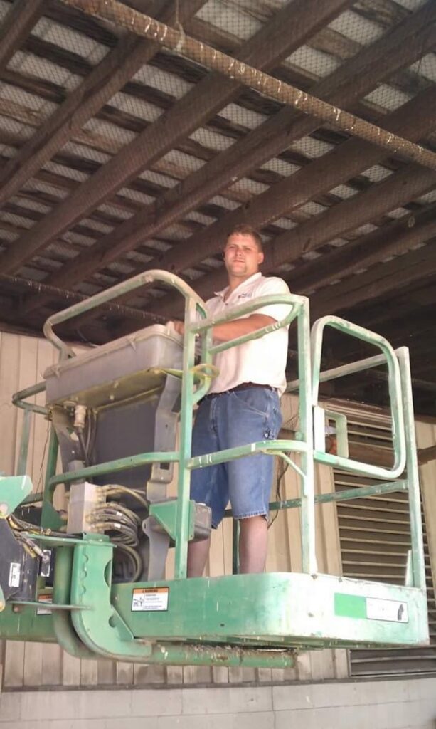 A D&J Pest Control technician in a scissor lift inspecting bird netting installed in a ceiling structure in Georgetown, KY.