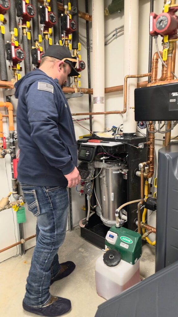 A technician inspecting a complex boiler or hydronic heating system by Utah Mechanical Heating and Air Conditioning in South Ogden, UT.