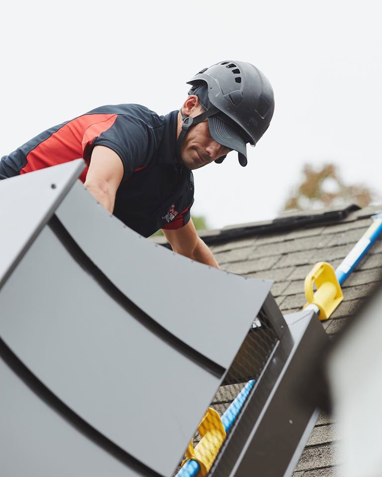 A technician from Owens Chimney Systems inspecting a chimney on a residential roof in Charlotte, NC.
