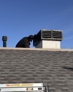 A technician inspecting a chimney vent on a roof for wildlife or pest entry points for Absolute Pest Solutions in Piedmont, OK.