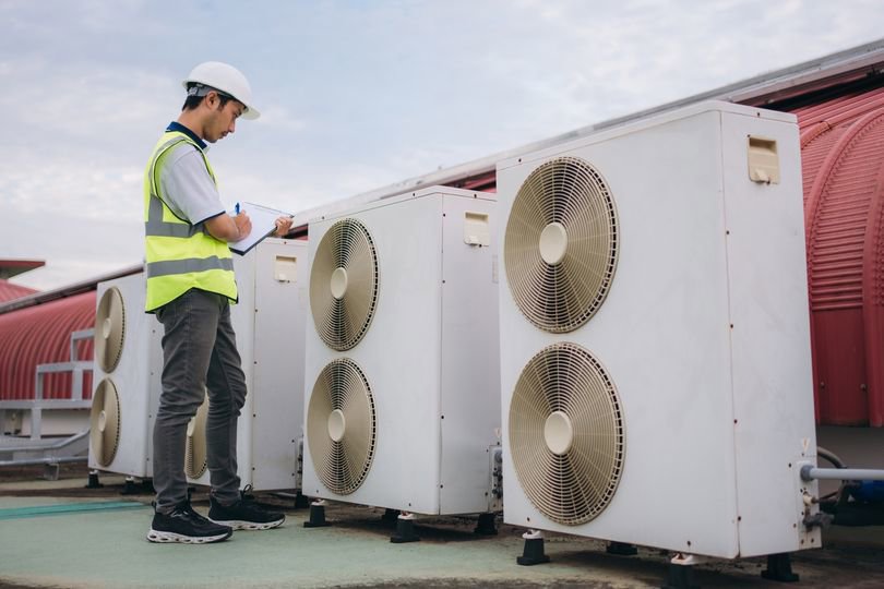 A technician inspecting commercial HVAC units on a rooftop for Isaac Heating & Air Conditioning in Rochester, NY.