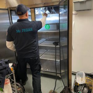 A Mr. Fridge technician inspecting the interior of a large commercial refrigerator in Seattle, WA.