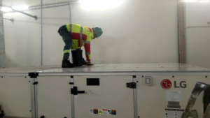 A Facilityfix technicians' HVAC contractor inspecting a large commercial rooftop HVAC unit in Port Harcourt, NG.