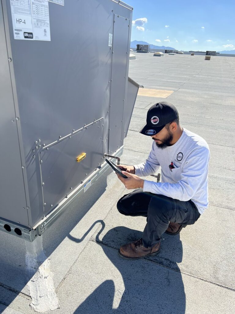 A technician inspecting a commercial rooftop HVAC unit with a tablet for maintenance by 365 Mechanical in Mesa, AZ.