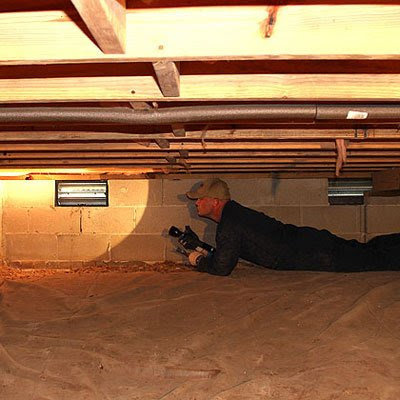 A technician inspecting a crawl space with a flashlight for Curry's Termite, Pest & Animal Control in Little Rock, AR