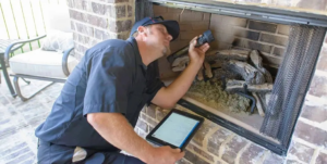A technician inspecting a fireplace with a flashlight and tablet for Denver Chimney Sweep in Denver, CO.