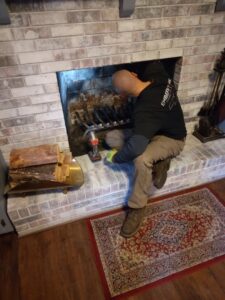 A technician from Emberstone Chimney Solutions inspecting a fireplace during a chimney sweep service in Charlotte, NC.