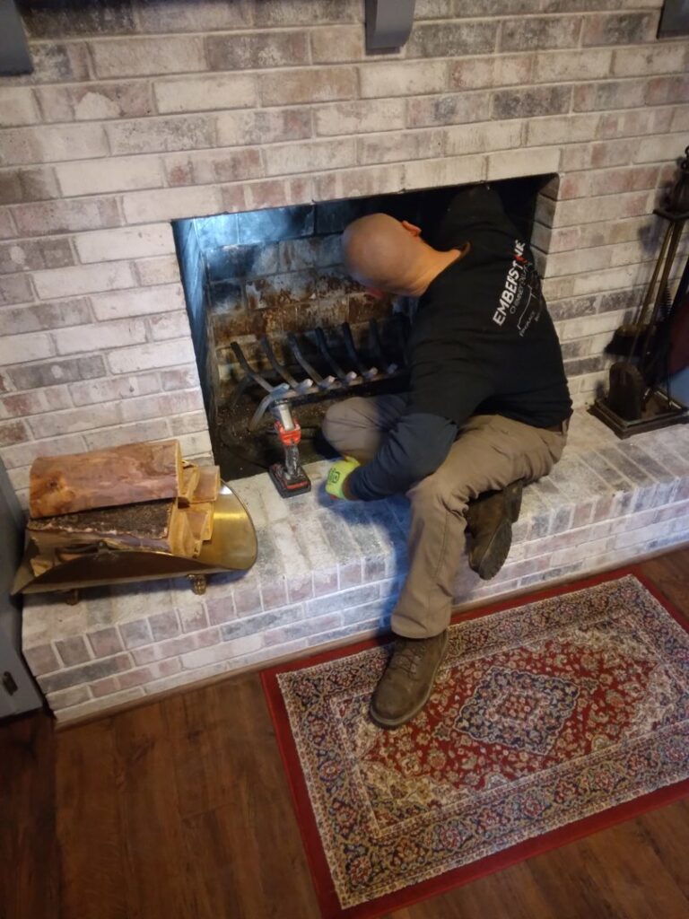 A technician from Emberstone Chimney Solutions inspecting a fireplace during a chimney sweep service in Charlotte, NC.