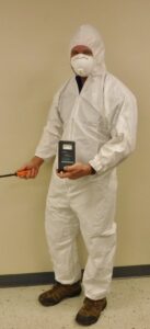 A technician in a hazmat suit inspecting for pests or moisture with a detection device for Ameri Care Services, Inc. in Murfreesboro, TN.