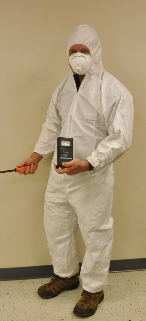 A technician in a hazmat suit inspecting for pests or moisture with a detection device for Ameri Care Services, Inc. in Murfreesboro, TN.