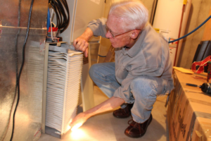 A technician inspecting or replacing an air filter in a furnace unit for West Wichita Heating & Air Conditioning in Wichita, KS.