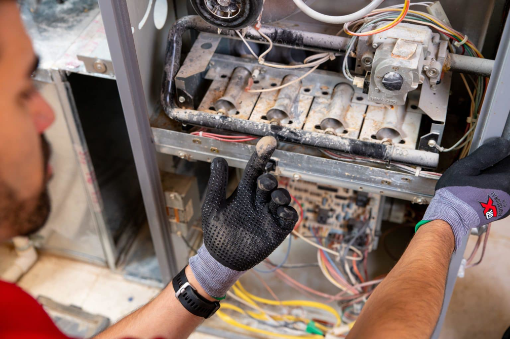 A technician inspecting the internal components of a furnace or air handler in Carmel, IN, by O'hare Heating and Air.