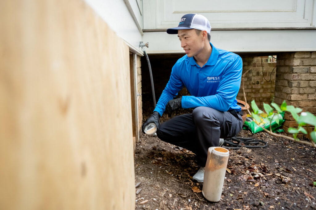 A Pest Authority Des Moines technician inspecting a house foundation for pests in Des Moines, IA.