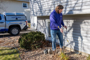 A technician inspecting the perimeter of a house for pests or wildlife at Abra Kadabra Pest and Wildlife in Forest Lake, MN.