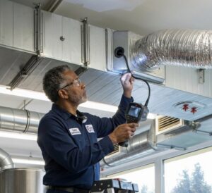 A technician inspecting HVAC ductwork with a borescope camera for RESTQ HVAC Repairs & Services in Rockville, MD.