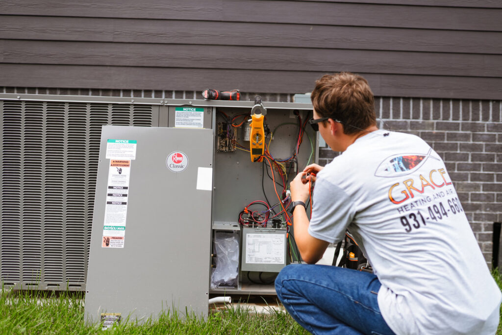 A technician inspecting the internal components of an outdoor HVAC unit for Grace Heating & Air in Clarksville, TN.