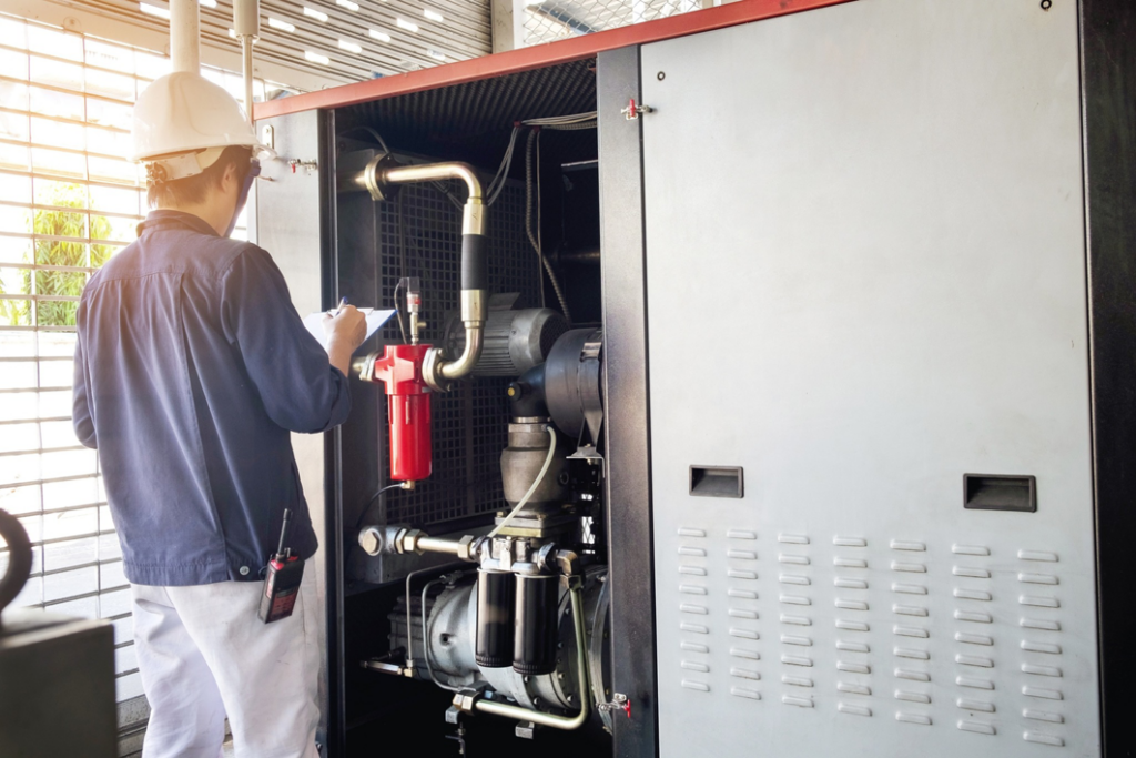 A technician inspecting a large industrial HVAC or compressor unit with a clipboard for Chrismon Heating & Cooling in Greensboro, NC.