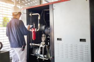A technician inspecting a large industrial HVAC or compressor unit with a clipboard for Chrismon Heating & Cooling in Greensboro, NC.