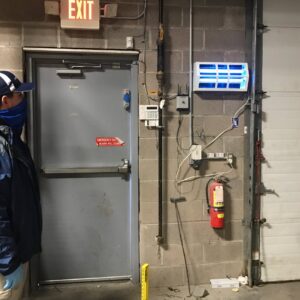 A Perimetek Pest Management technician inspecting an insect light trap in East Syracuse, NY, as part of pest control services.