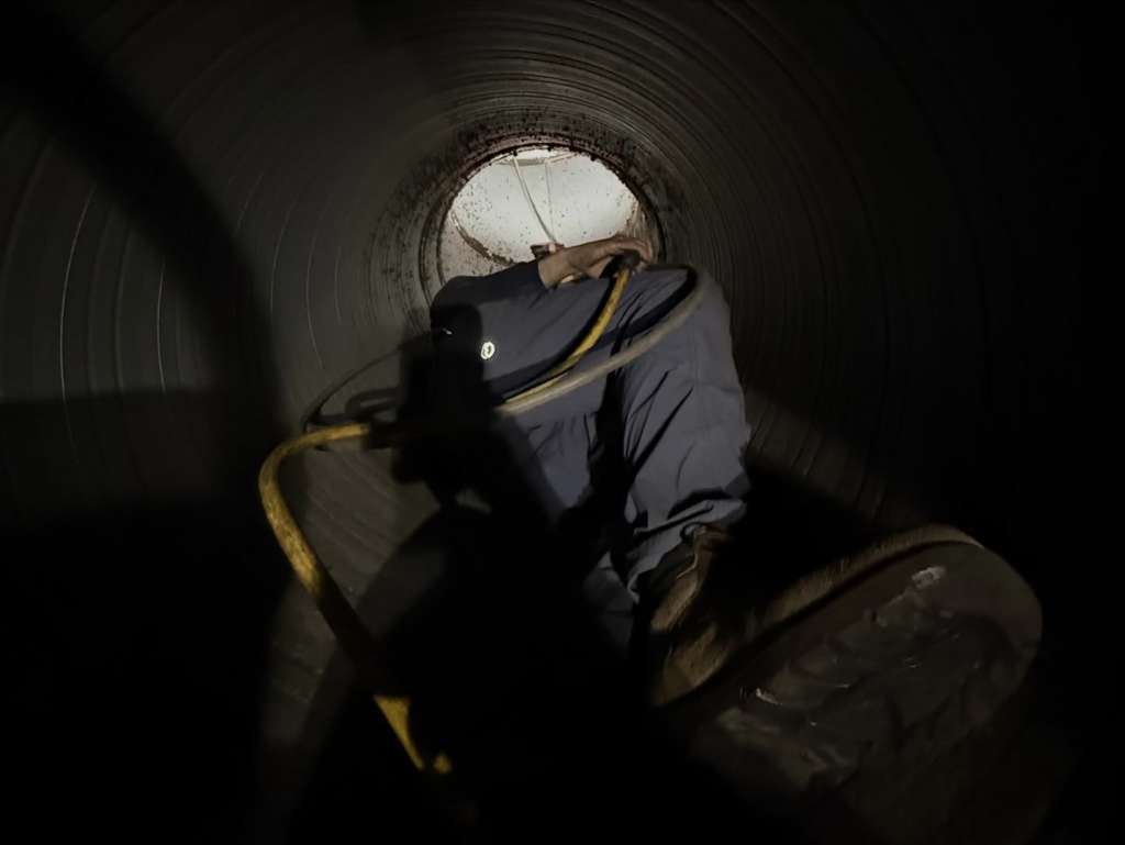 A Duct Doctor of Baton Rouge, LA technician inspecting the interior of a large air duct during a comprehensive cleaning service.