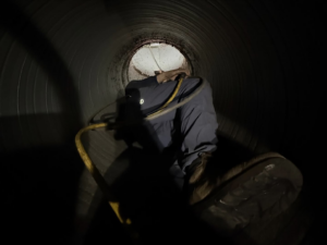 A Duct Doctor of Baton Rouge, LA technician inspecting the interior of a large air duct during a comprehensive cleaning service.
